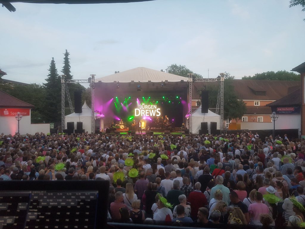 blick von der technik auf die buehne, zuschauer feiern, buehne mit lichtshow, kuenstler, juergen drews